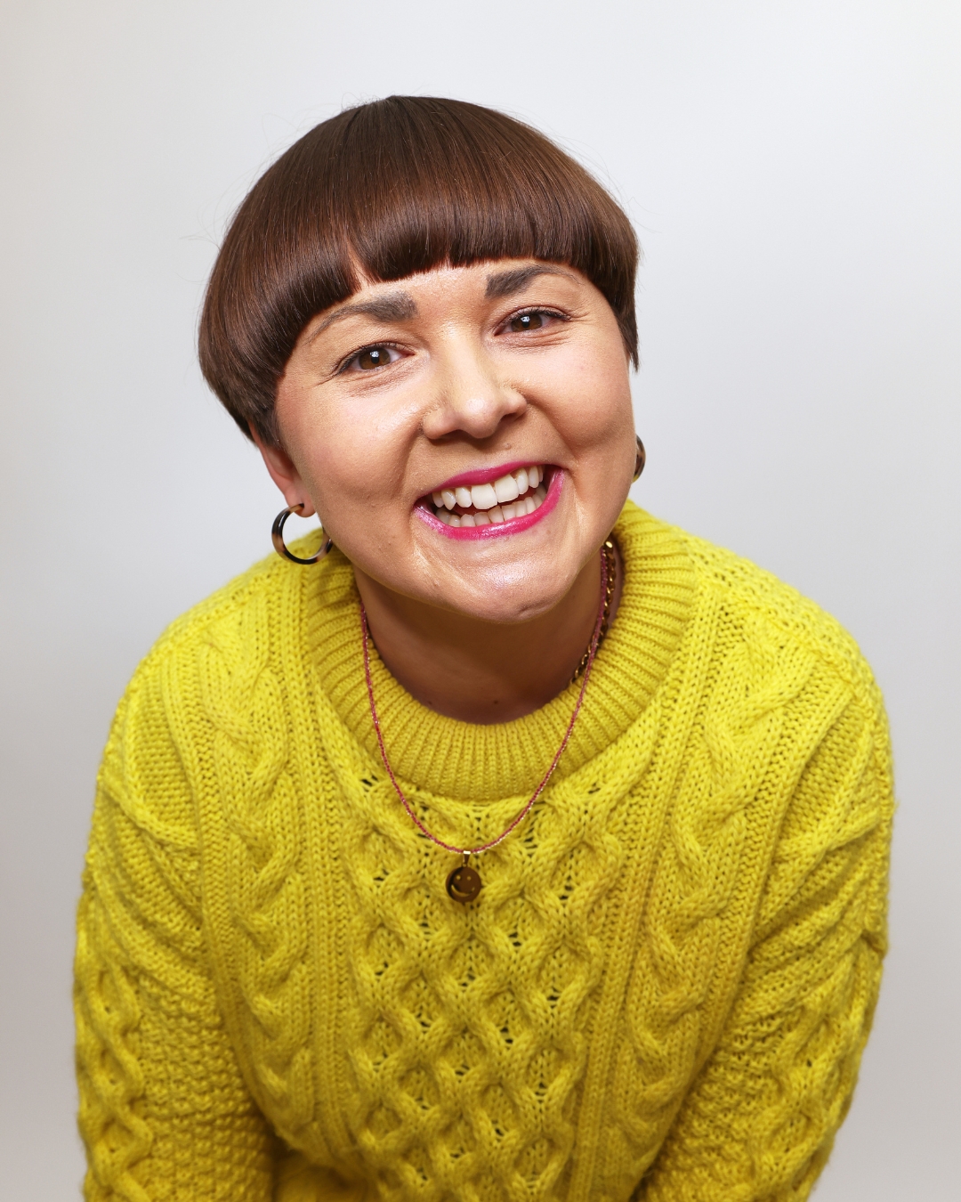 Beth, founder of Live Happy Creative, smiling in a bright yellow jumper