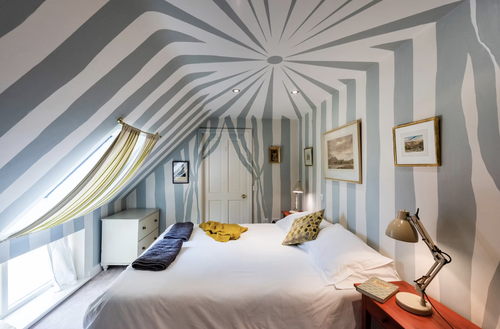 Quirky double bedroom painted with blue and white circus-tent stripes