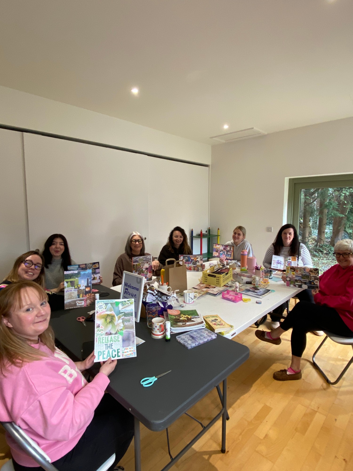 Group of women smiling at a craft table making vision board collages at a Revive workshop